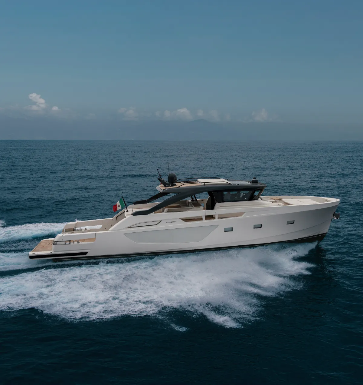 Side view of a Bluegame BG Range yacht cruising at speed, emphasizing its sporty profile, flush deck, and signature hull lines.